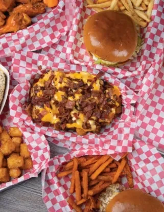 Spread of comfort food: loaded fries, burger, fried chicken, and tater tots.
