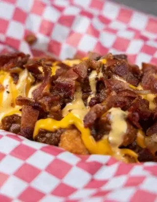 Loaded tater tots or fries with melted cheese, white sauce, and bacon.