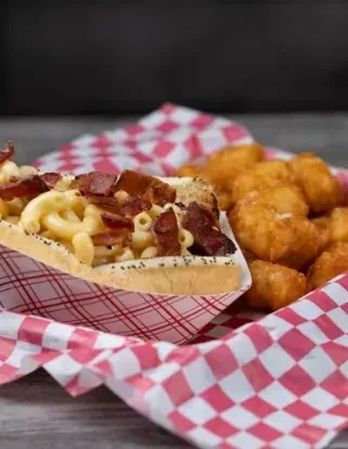Mac and cheese hot dog topped with bacon, served with tater tots.