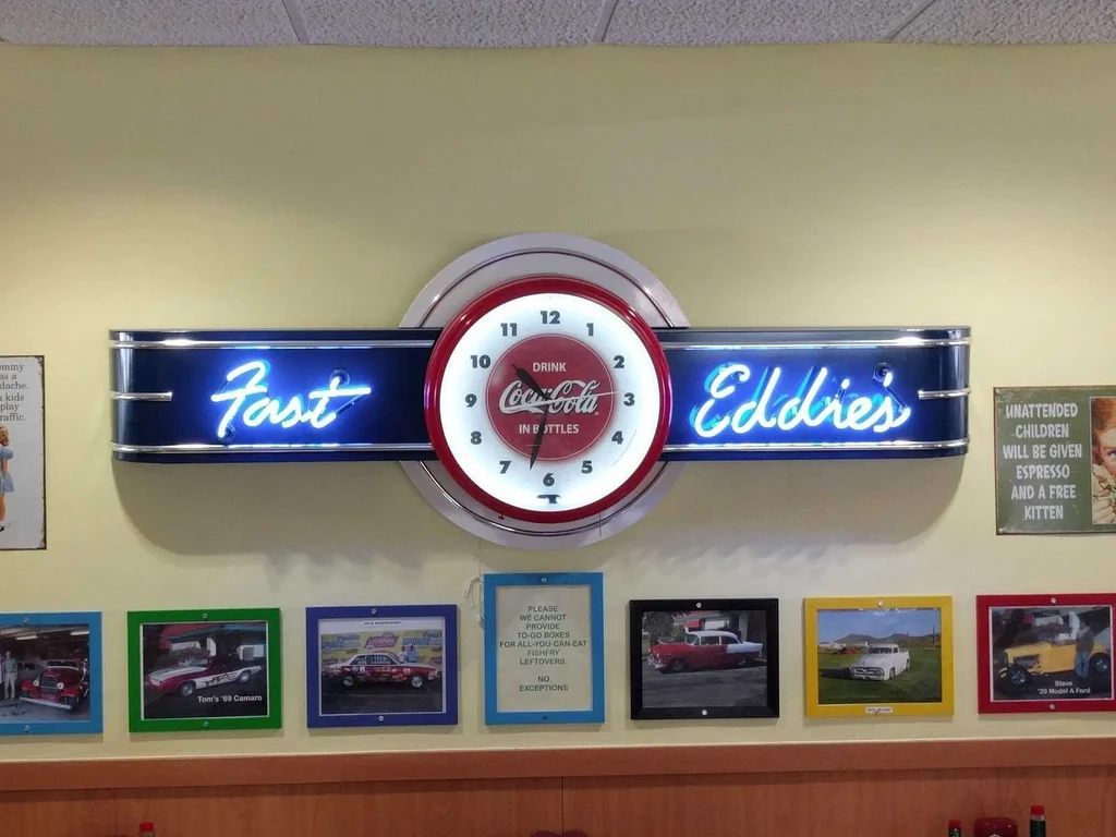Illuminated "Fast Eddies" sign, Coca-Cola clock, and classic car pictures.