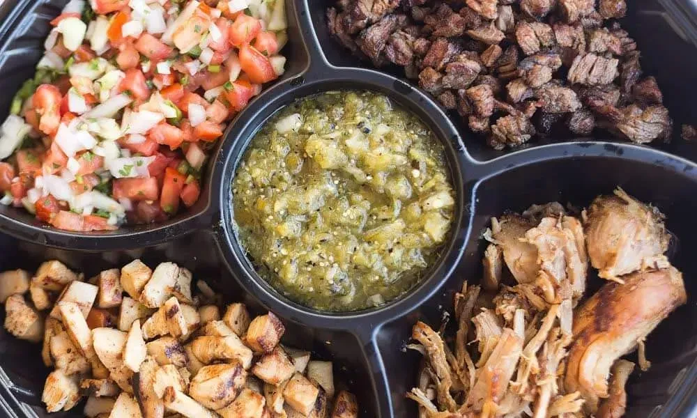 Black five-compartment platter with pico, green salsa, chicken, and two meats.