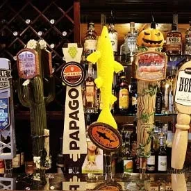 Close-up of beer tap handles, liquor bottles, and an autumn pumpkin.