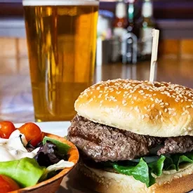 Close-up of a classic burger, side salad, and frosty beer.