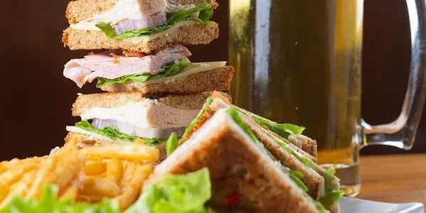 Club sandwich, golden french fries, and a mug of beer.