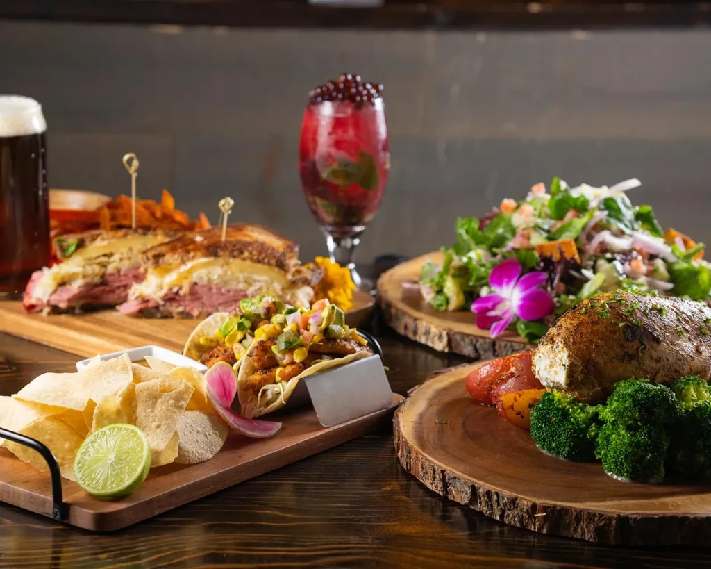 Vibrant spread of tacos, sandwich, roasted entree, salad, and cocktails.