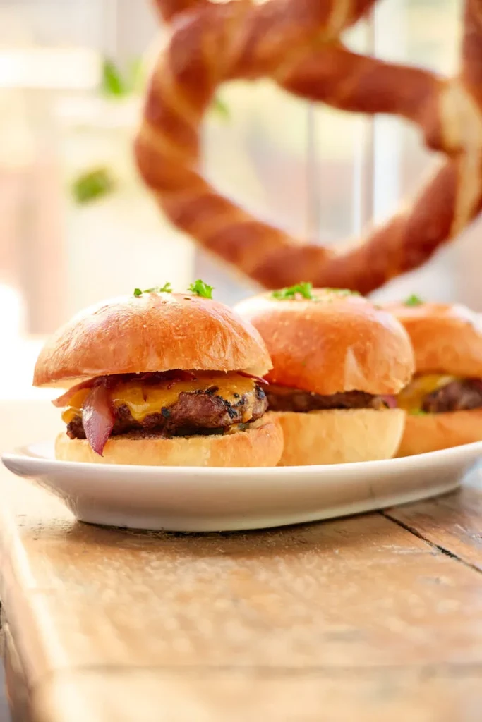 Three mini burgers with cheese, meat, onion, and herbs.