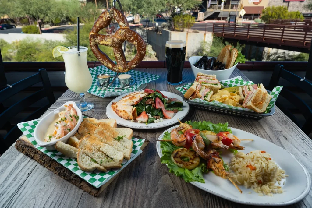 Variety of food and drinks on a rustic outdoor patio table.