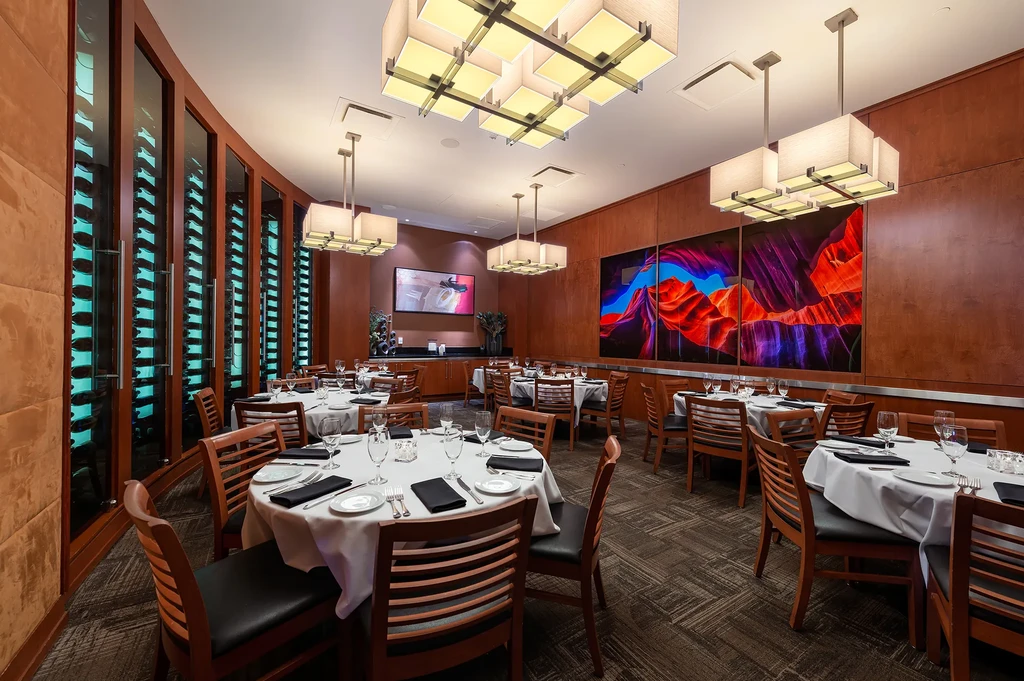 Upscale restaurant dining room with wine display and vibrant triptych art.