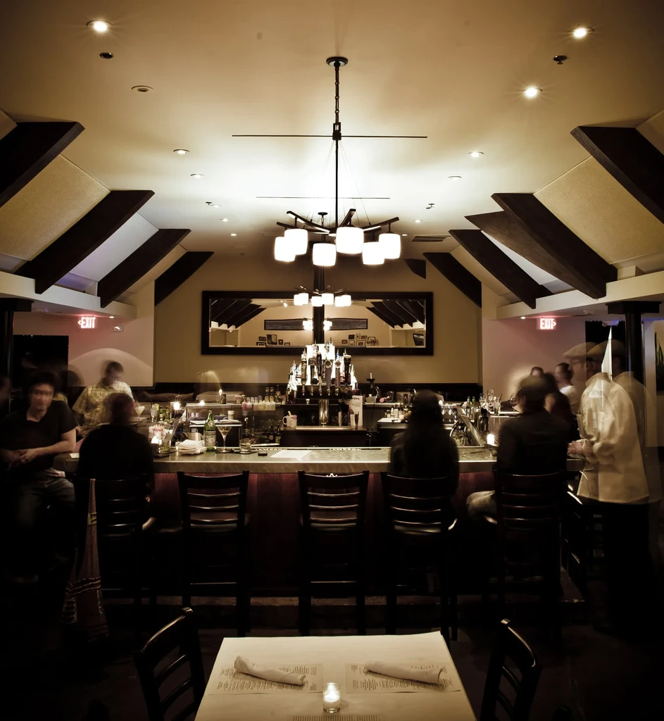 Warmly lit, upscale bar interior with motion-blurred patrons.