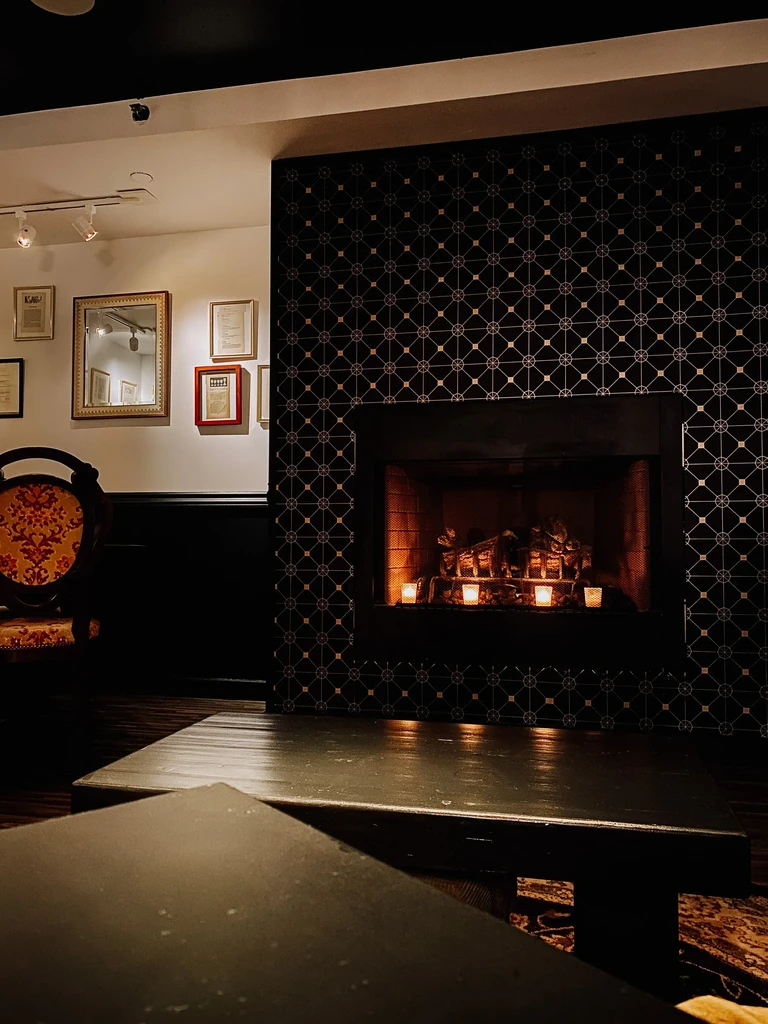 Cozy lounge with a glowing geometric-tiled fireplace and soft lighting.