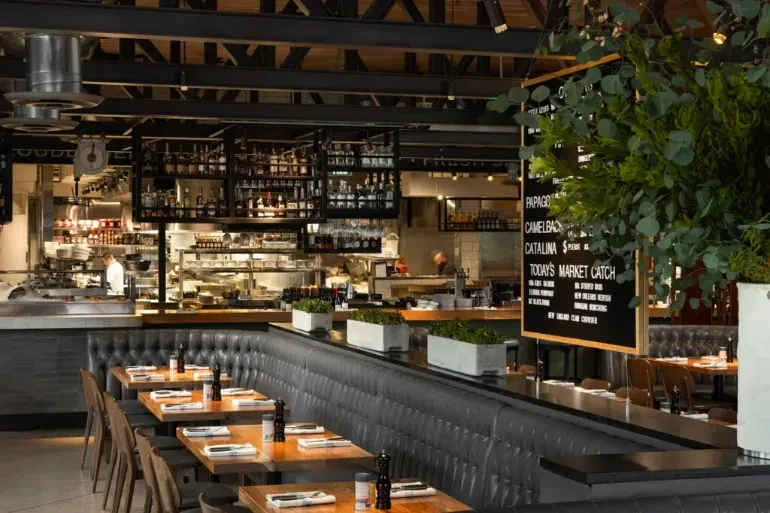 Modern upscale restaurant interior with booth, open kitchen, industrial-chic style.