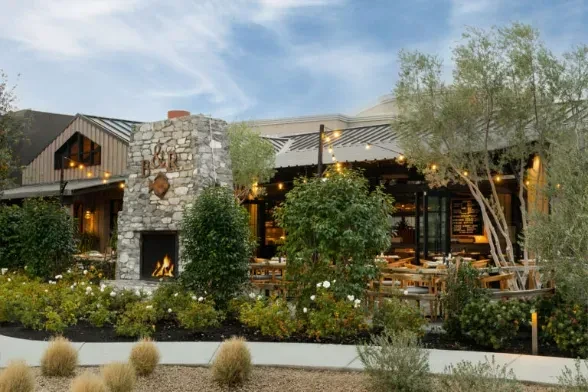 Modern rustic restaurant with B&R stone fireplace, lit fire, and patio.