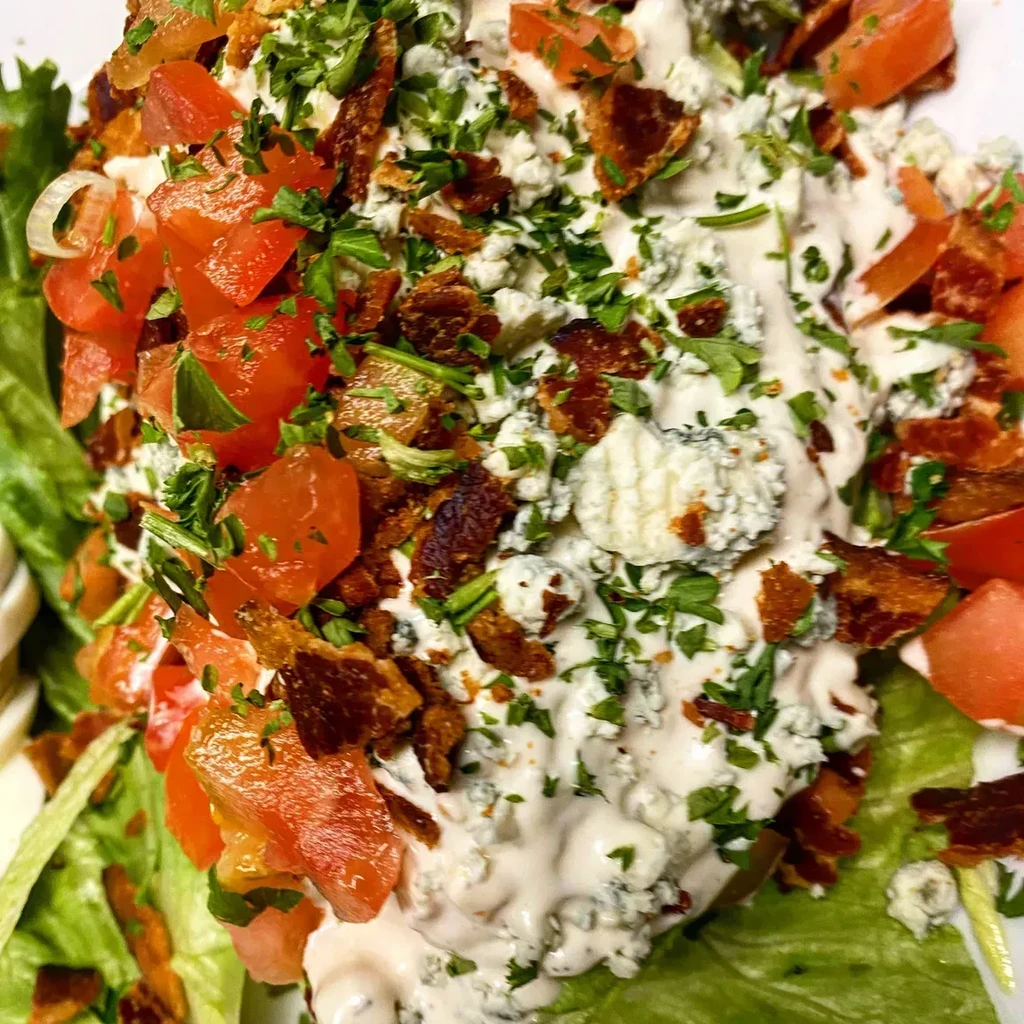Salad with blue cheese dressing, diced tomatoes, and crispy bacon.
