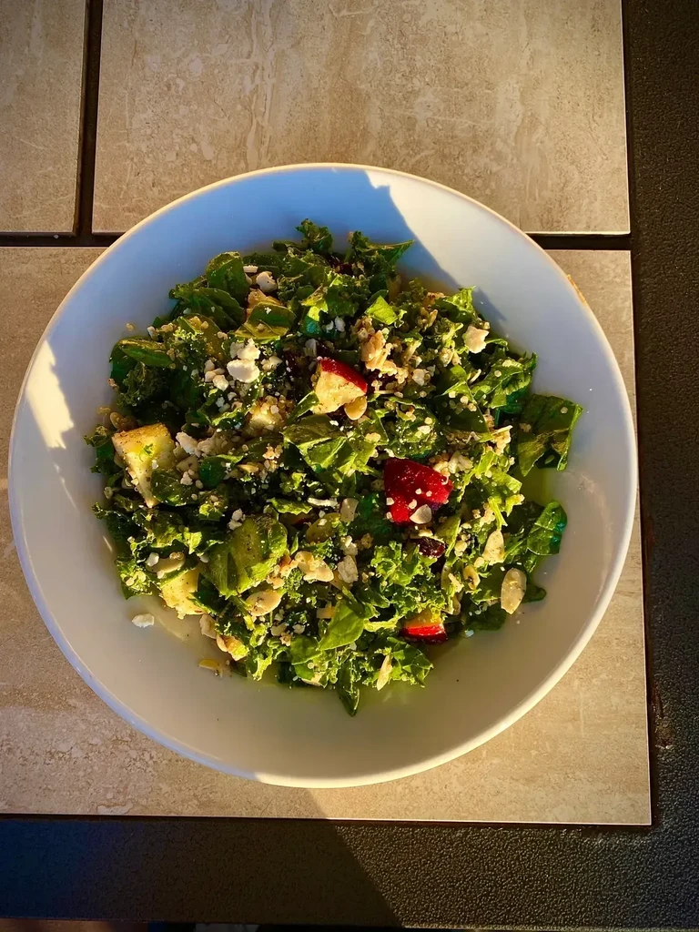 Fresh salad with greens, feta, fruit, nuts, and croutons, top-down view.