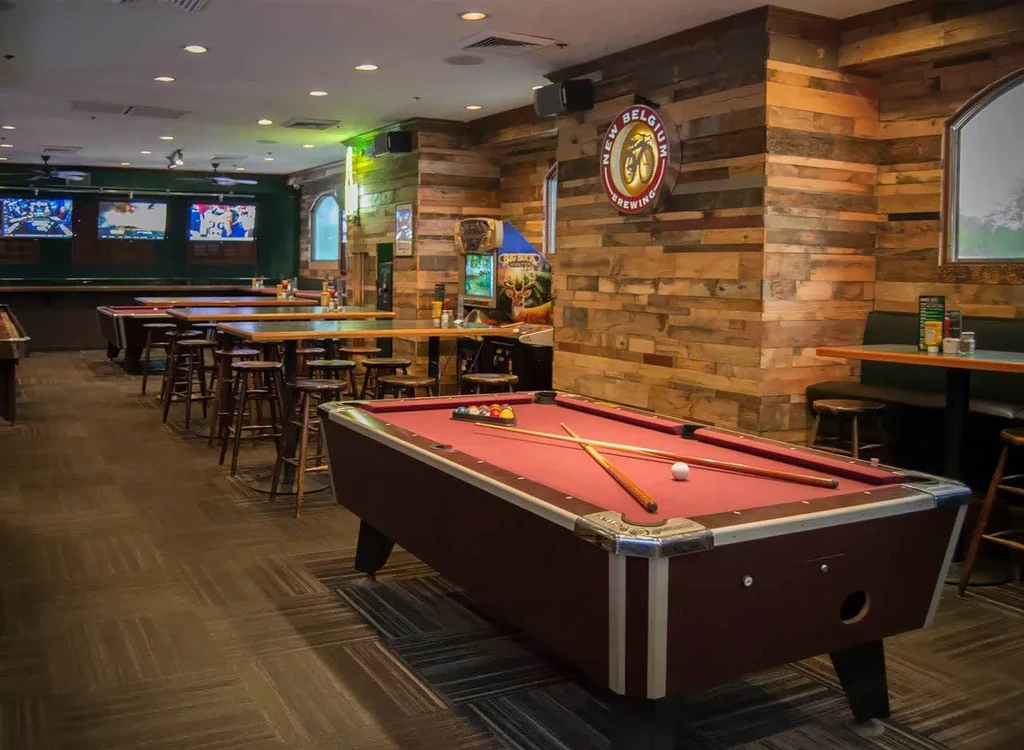 Casual sports bar game room with pool tables, TVs, and arcade.