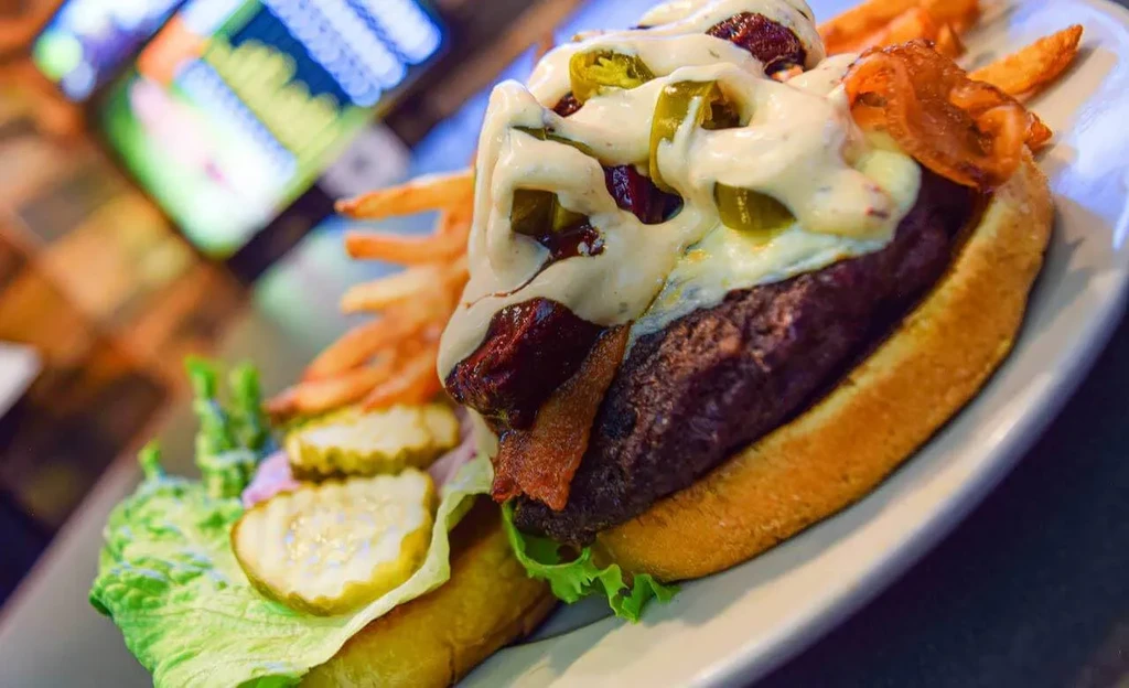 Close-up of a gourmet burger with bacon, jalapeños, and golden fries.