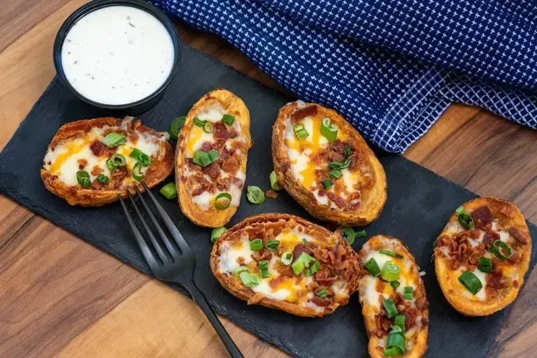 Six potato skins with melted cheese, crispy bacon, and chives.