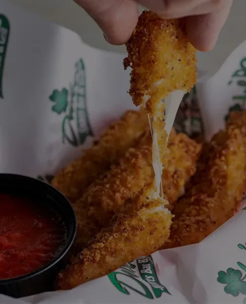 Hand lifts fried cheese stick, showing melted cheese stretching.
