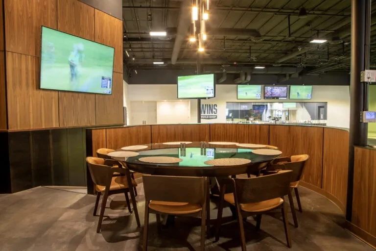 Modern sports bar interior with empty table and televisions showing golf.