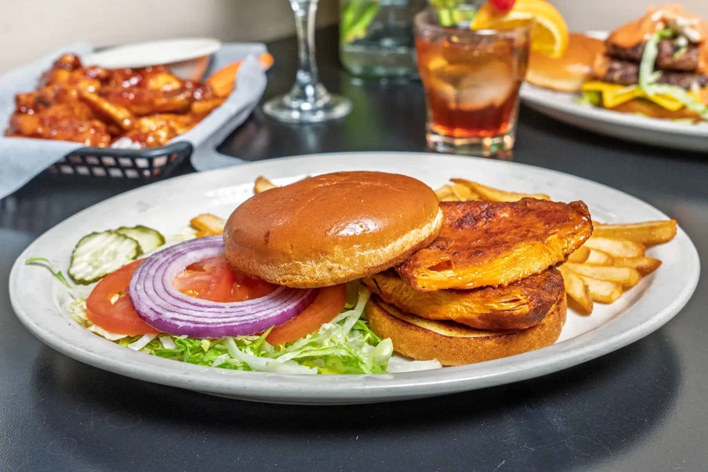 Grilled sandwich, fries, cocktail, and other food on a table.