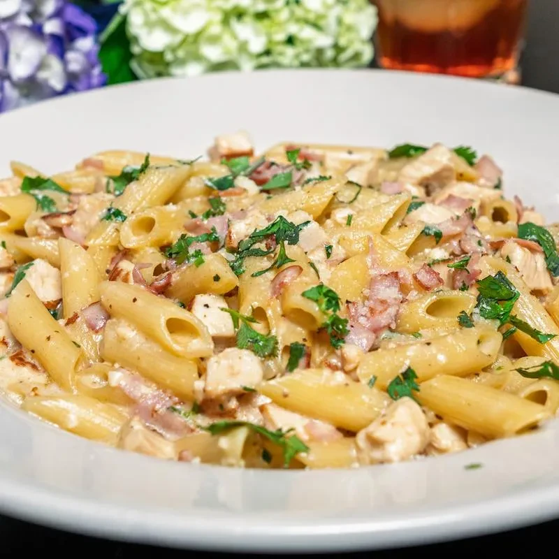 Creamy penne pasta with chicken, bacon, and fresh herbs.