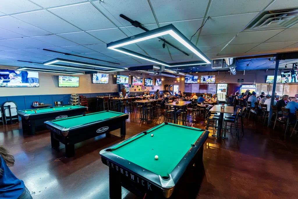 Lively restaurant interior with three pool tables, TVs, and dining areas.