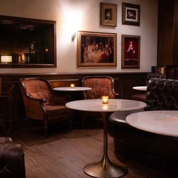Elegant, dim-lit bar lounge with ornate seating, marble tables, and candles.