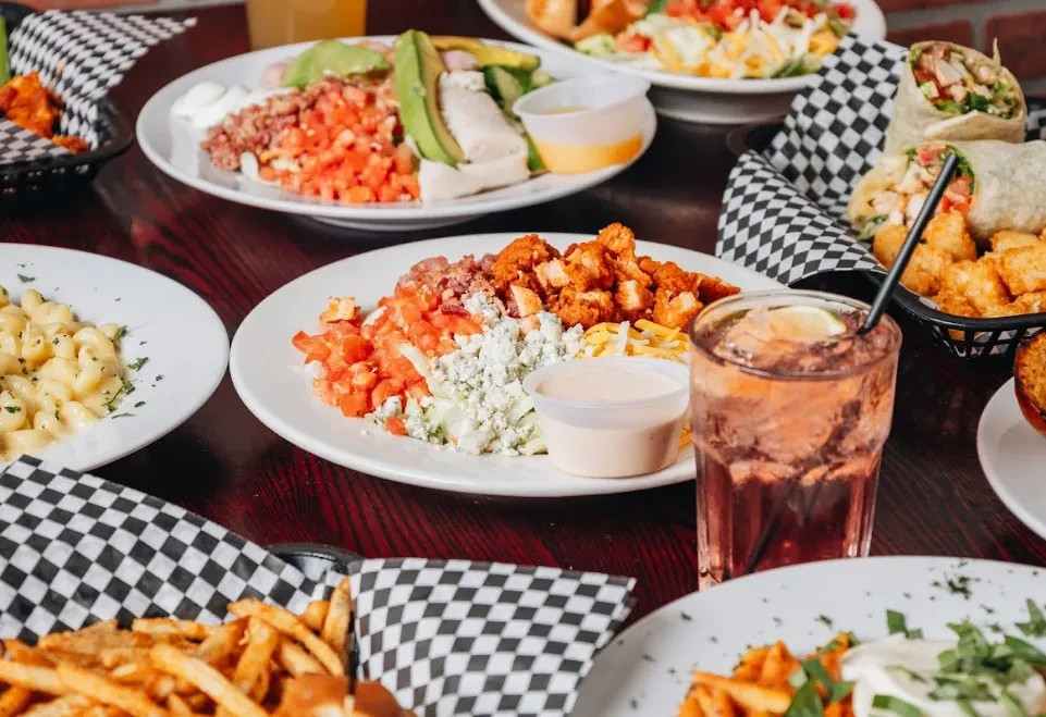 Restaurant table with french fries, macaroni, salad, chicken, and a beverage.