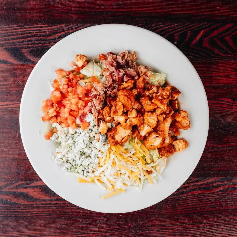 Salad with crispy chicken, bacon, tomatoes, blue cheese, and shredded cheese.