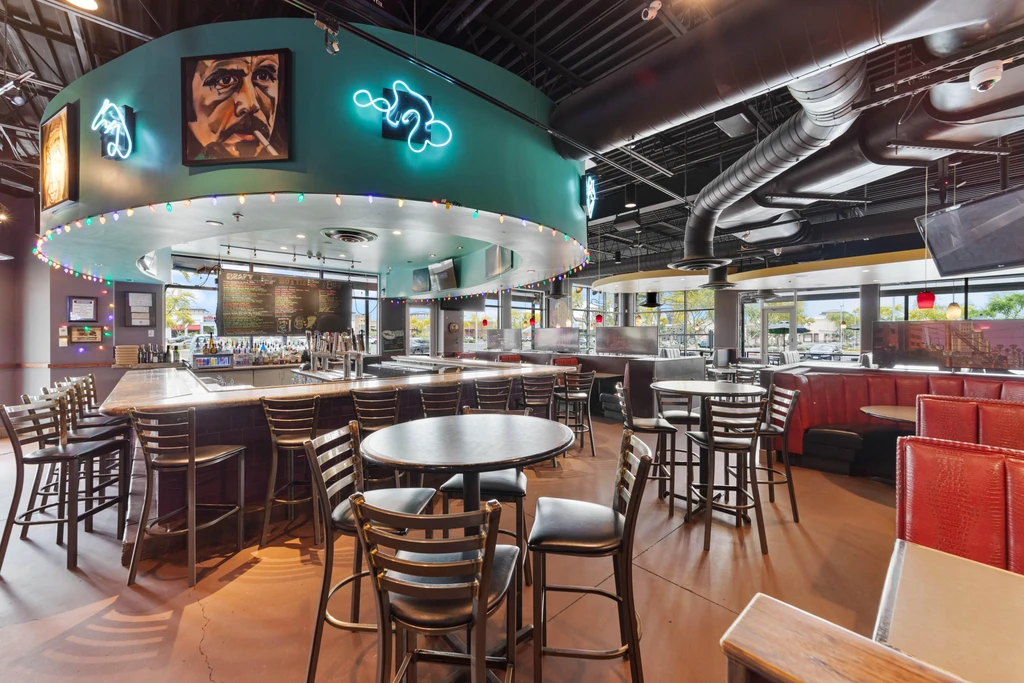 Industrial bar and restaurant interior with teal arch and red booths.