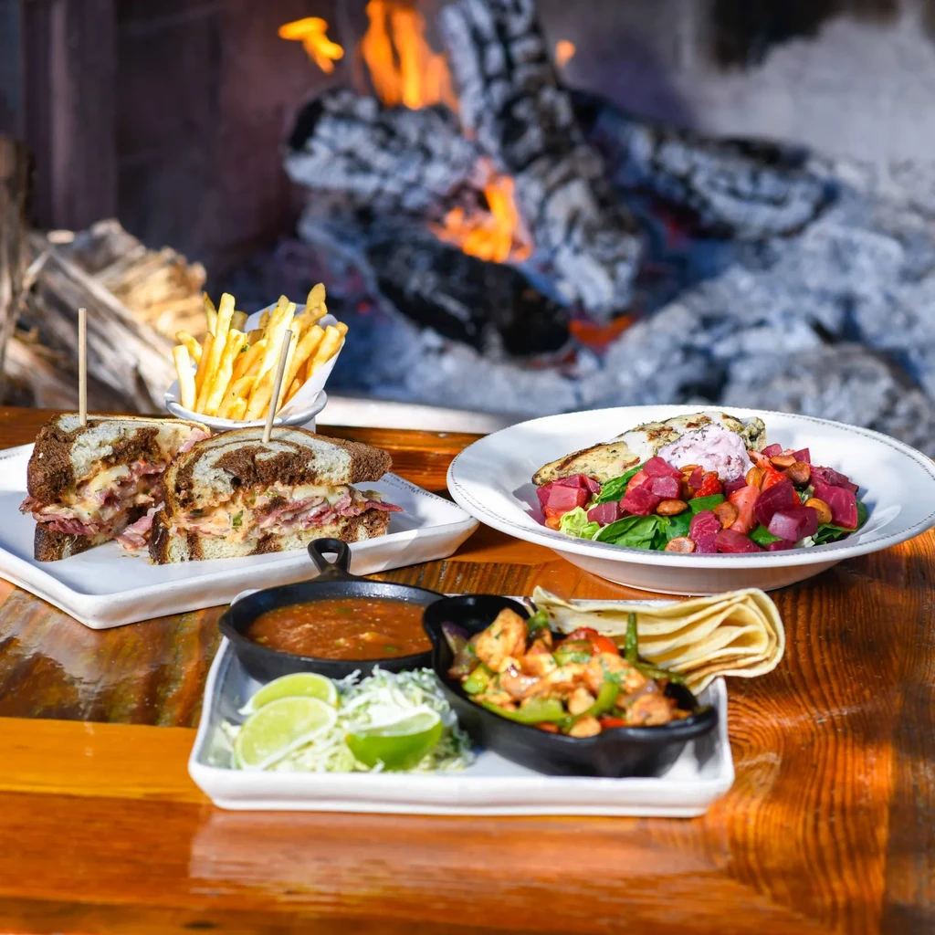 Three distinct dishes: fajitas, sandwich, and salad on a rustic table.