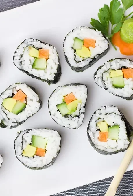 Eight colorful maki sushi rolls with avocado, cucumber, carrot, and garnish.