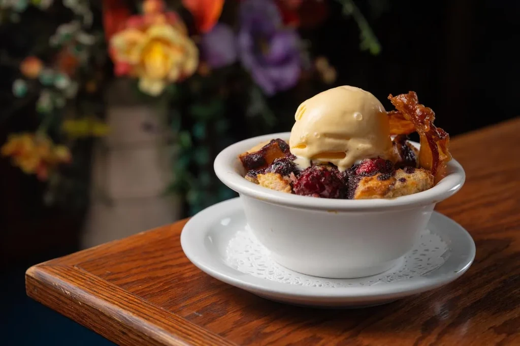 Berry crisp with melting vanilla ice cream and a crispy garnish.