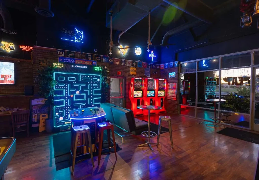 Arcade bar interior with neon signs and a large Pac-Man game.