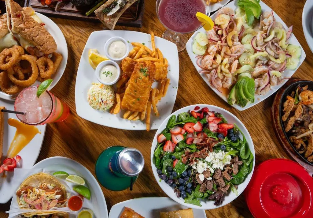A large spread of diverse dishes and drinks on a wooden table.