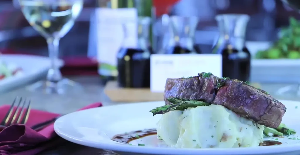 Grilled steak with herbs, mashed potatoes, asparagus, and sauce.