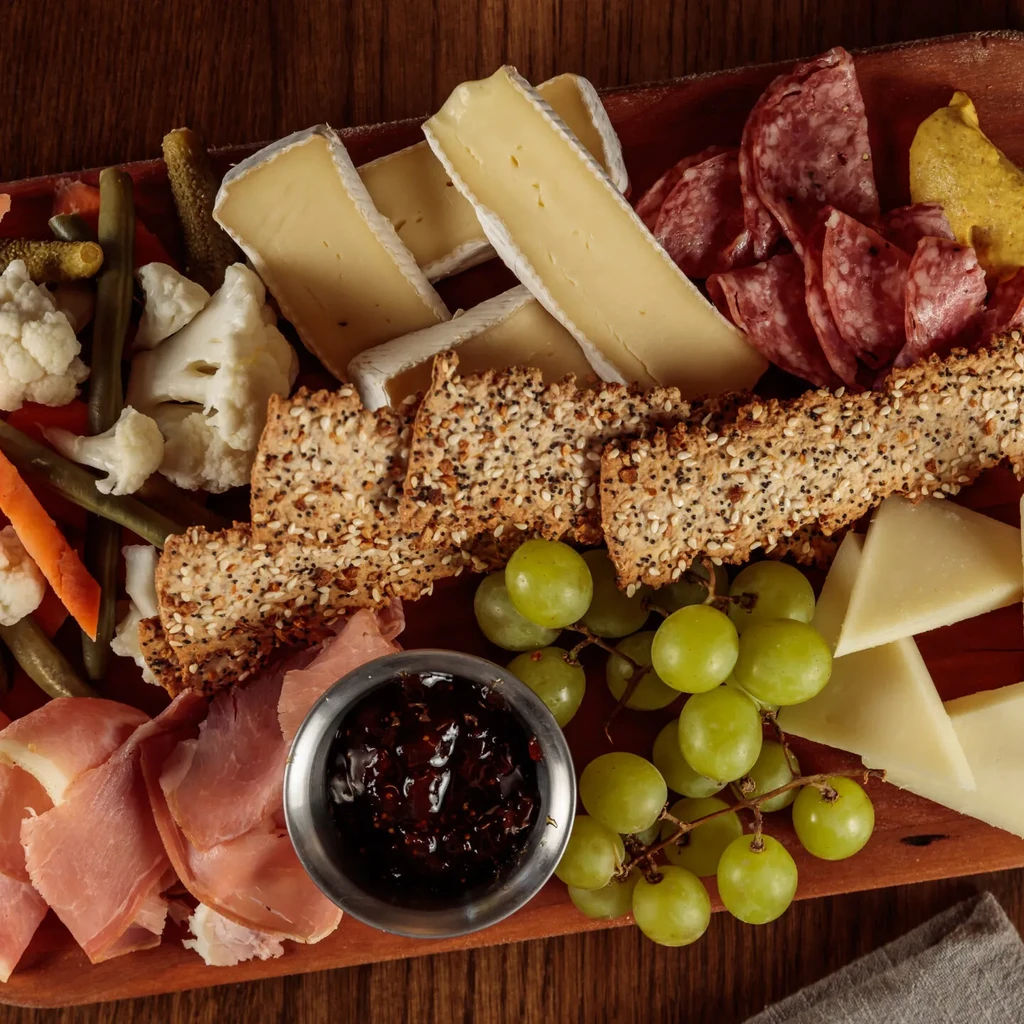 Close-up: Charcuterie and cheese board with meats, cheeses, grapes, crackers.