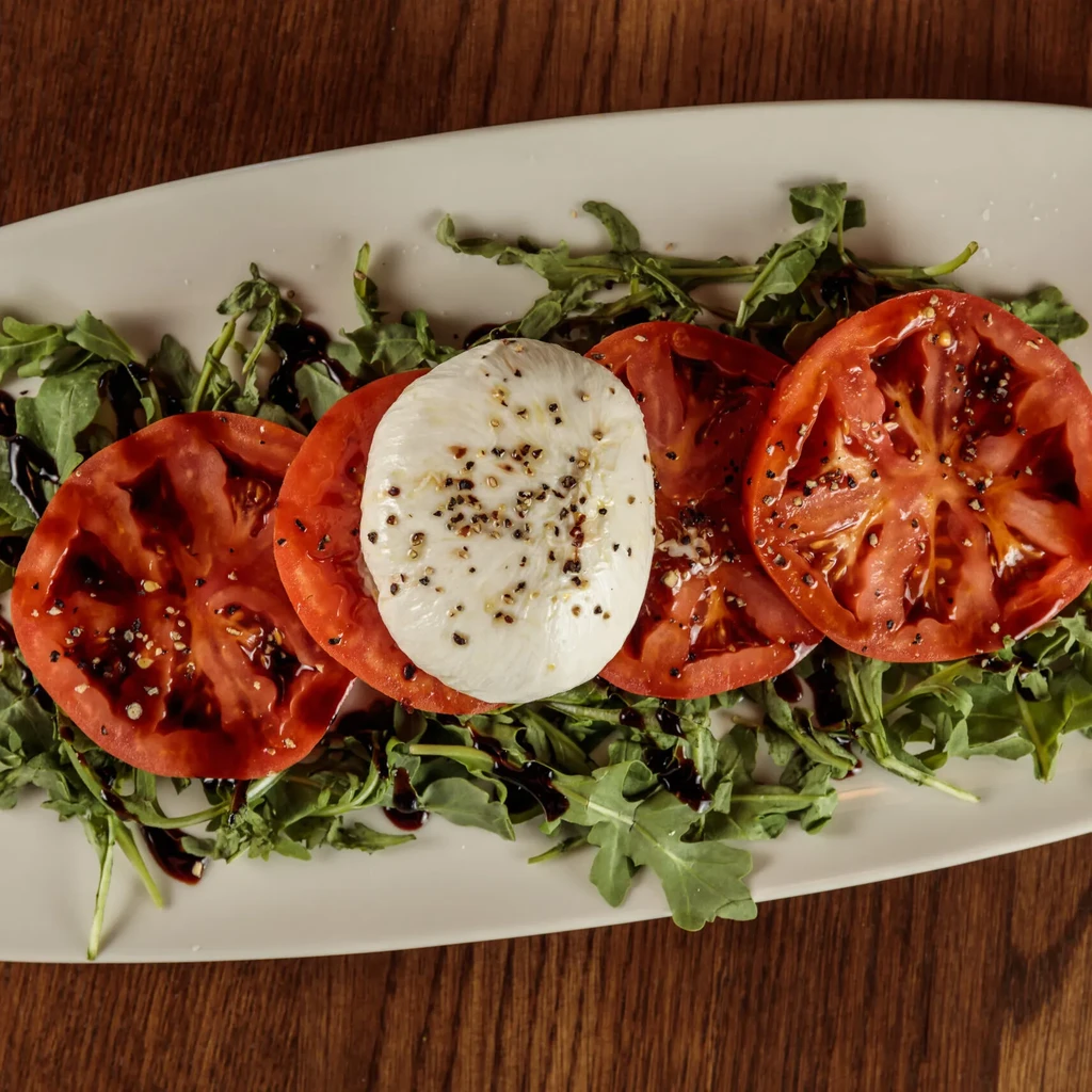 Caprese salad with tomatoes, mozzarella, arugula, and balsamic glaze.