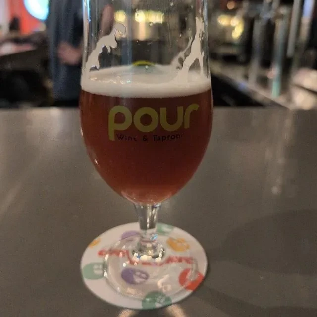 Stemmed glass of reddish-brown beer, "pour Wine & Taproom" branding.