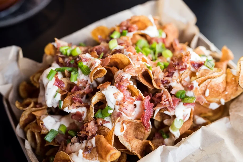 Wavy potato chips loaded with creamy sauce, bacon, and green onions.