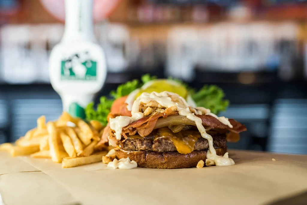 Close-up of a gourmet burger with melted cheese, bacon, and fries.