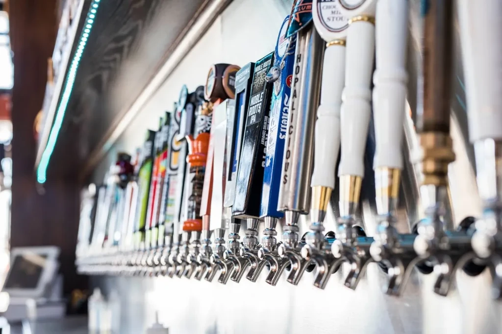 Long row of diverse beer tap handles in a modern bar.