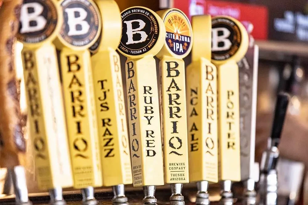Row of yellow Barrio beer tap handles in a bar.