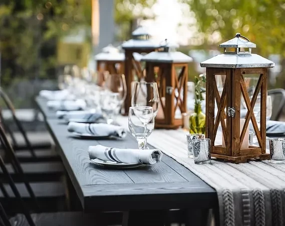 Outdoor table set with rustic lanterns, dinnerware, and greenery.