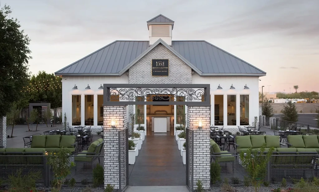 Exterior of Joanie Batten modern bistro with lit patio at dusk.