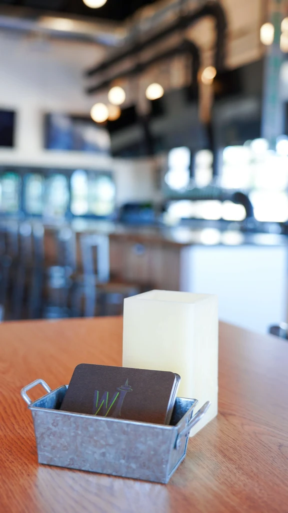 Metal tin with 'W' logo cards and block on a wooden table.