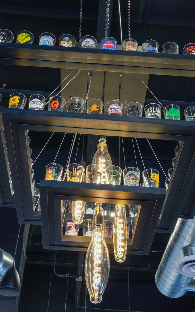 Industrial light fixture displaying branded shot glasses and Edison bulbs.