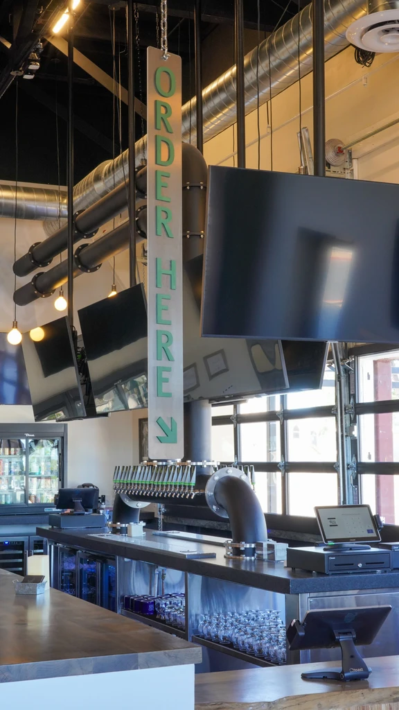 Empty modern industrial bar with beer taps and "ORDER HERE" sign.