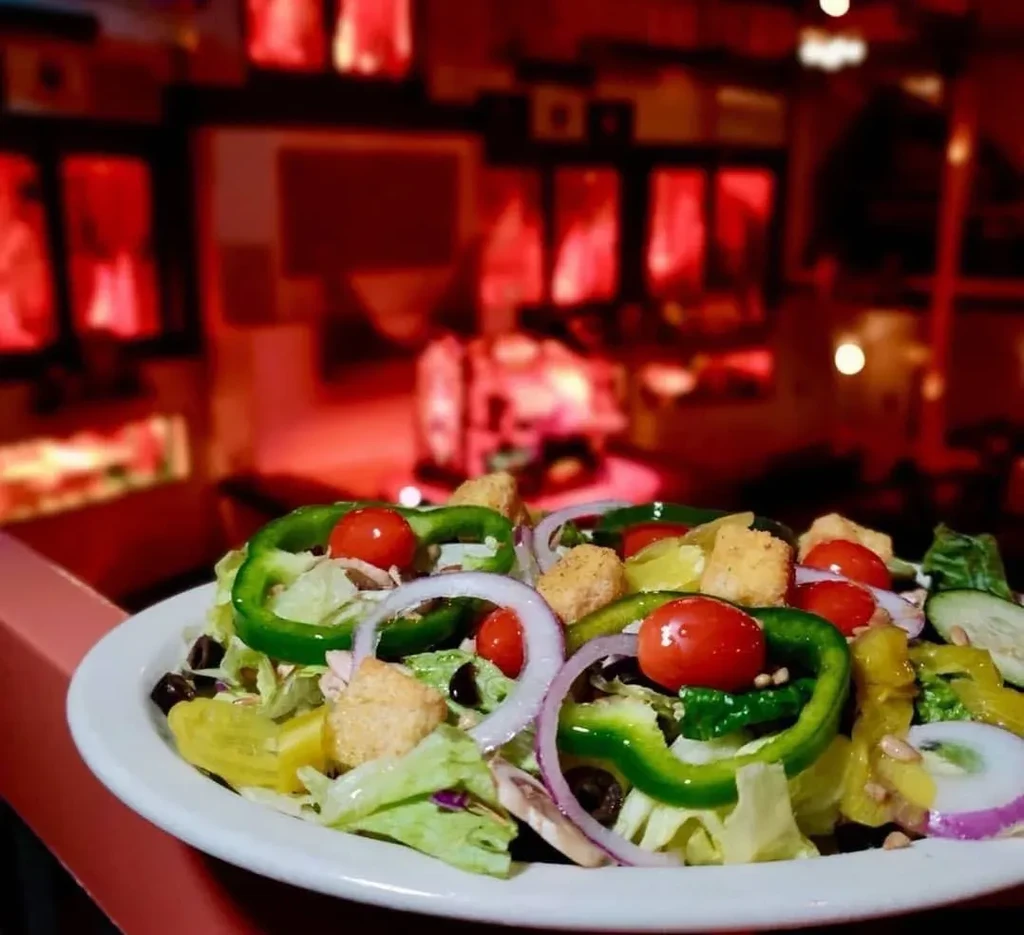 Fresh garden salad with colorful ingredients against a blurred red background.