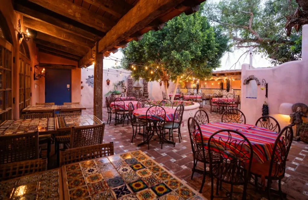 Outdoor Southwestern restaurant patio with striped tables and string-lit tree.